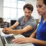 Deux managers sont devant leur ordinateur et se forment à un outil informatique