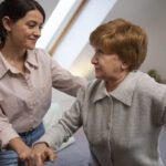 Une jeune femme aide une femme pus âgée à se lever